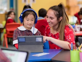 A student with headphones on head with teacher